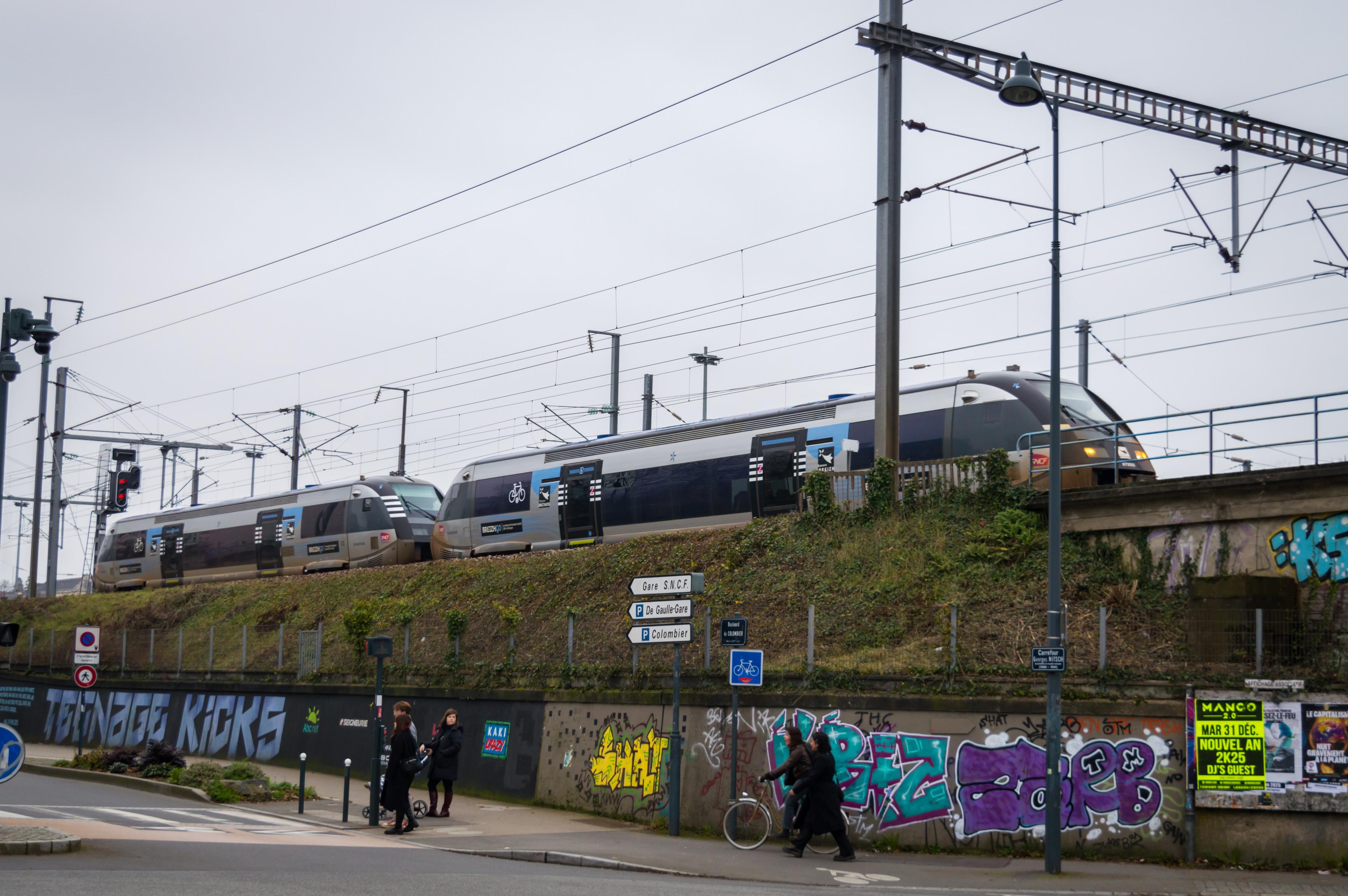 Two small TER Bretagne trains couples pass on a bridge over the road. Different angle