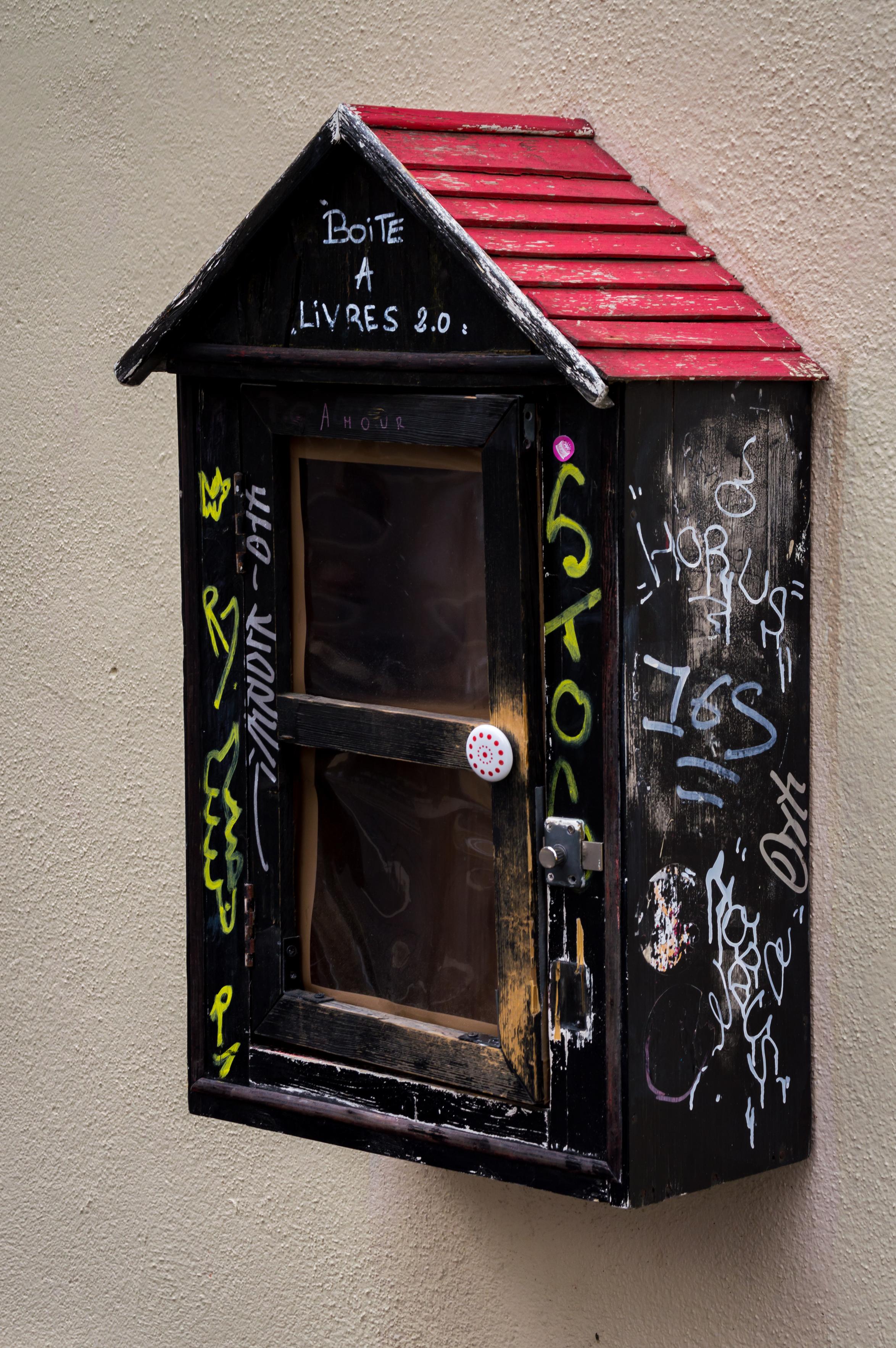Communal bookshelf on the wall of a building. "Boite a livres 2.0"